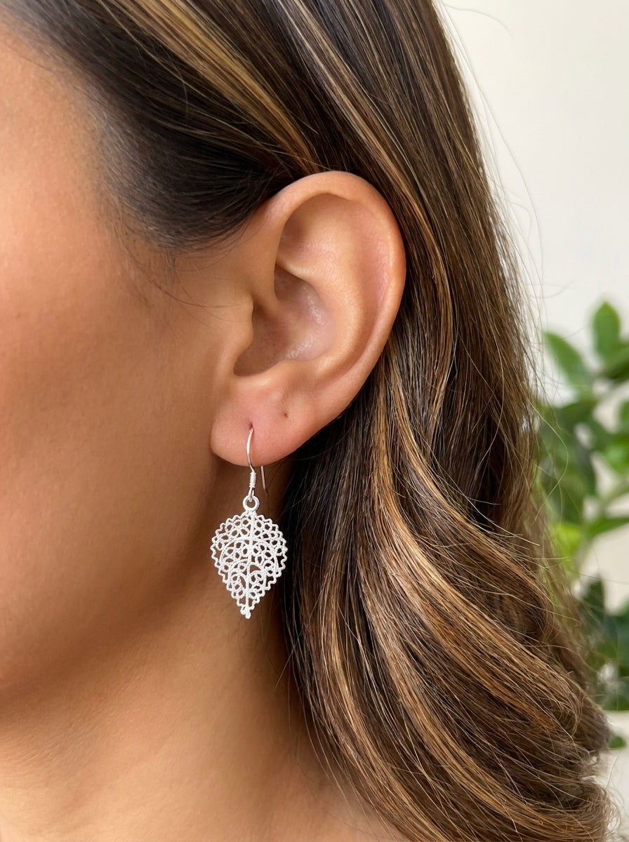 Aretes Hojas de Diantus GAIAM puestos en la oreja, detalle macro